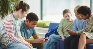 Children sit together using digital devices.