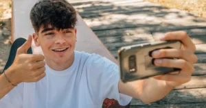 A teen boy takes a video outside.