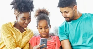 A family looks at a smartphone together.