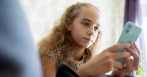 A pre-teen child uses a smartphone.