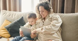 A mother using a tablet with her young son.